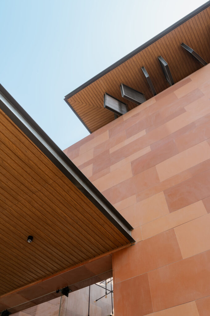 Architectural view looking up at wooden soffits and terracotta walls for facade material selection.