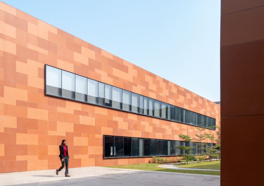 Person walking past a terracotta wall demonstrating facade material selection in modern architecture.