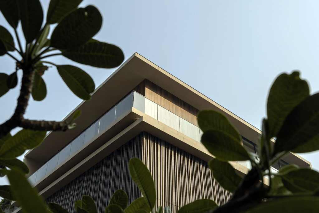 Modern facade material selection showcasing choosing facade materials behind green leaves.