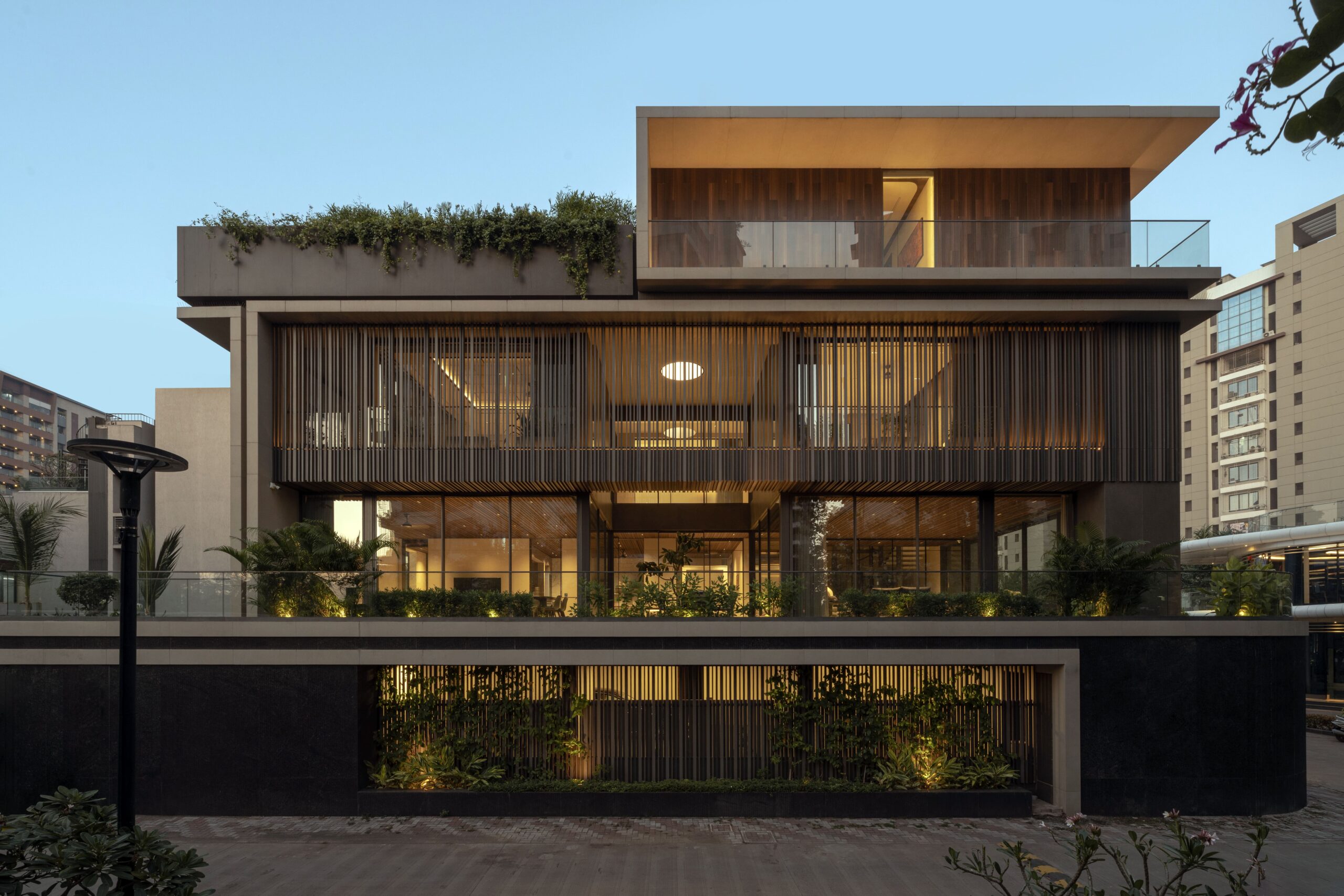 Modern residential building facade featuring different levels, integrated green roofs, and wood-look panels.