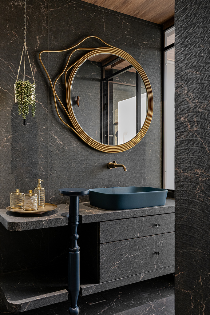 Dark marble-effect sintered surface in a bathroom interior with veining and mineral variation visible under warm lighting