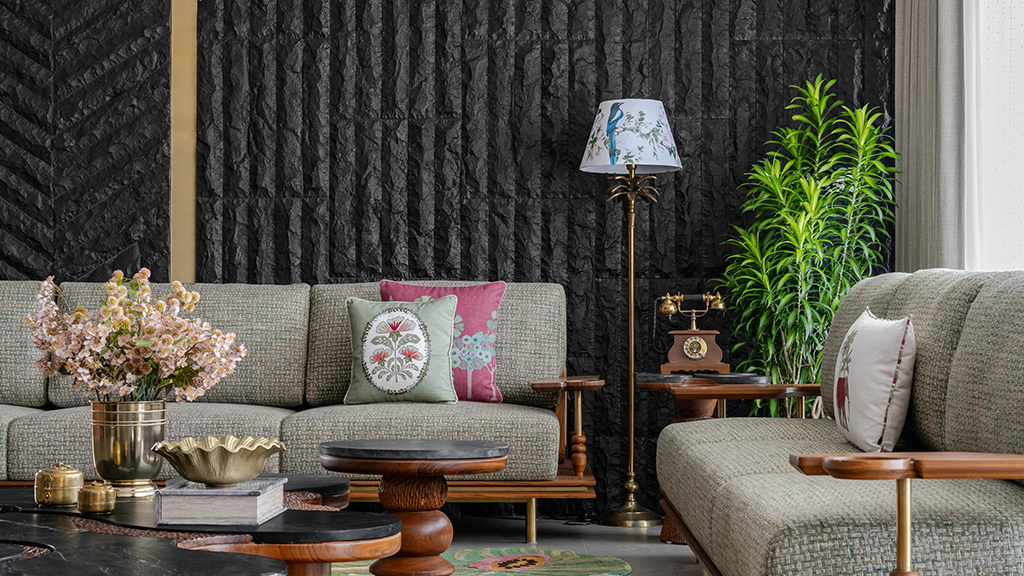 Dark raw textured wall surface with deep irregular relief in a living room setting with plants and natural light